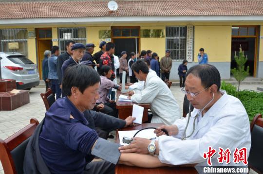 图为白河村村委会院子里,留守村民排队进行体检。 冯志军 摄 图为白河村村委会院子里,留守村民排队进行体检。 冯志军 摄