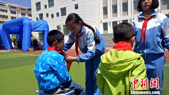 图为西宁市南川西路小学的少先队员向儿童福利院的小朋友佩戴红领巾。 张海雯 摄 图为西宁市南川西路小学的少先队员向儿童福利院的小朋友佩戴红领巾。 张海雯 摄