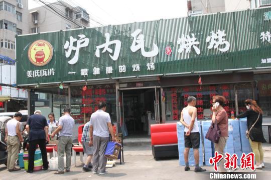 饮虎池街一烧烤店老板正在店铺门口甩卖桌、椅、纸巾等物品。 赵晓 摄 饮虎池街一烧烤店老板正在店铺门口甩卖桌、椅、纸巾等物品。 赵晓 摄
