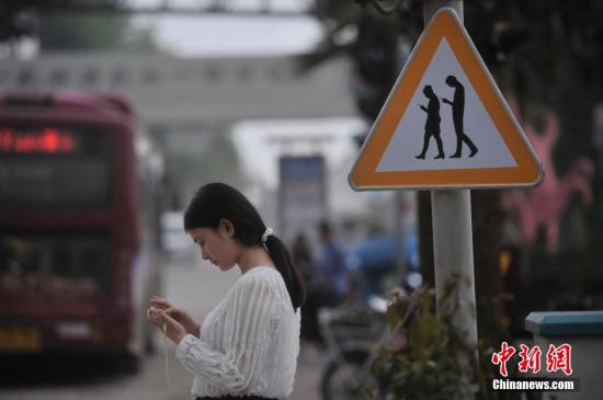 重庆涪陵红酒小镇一红绿灯处摆放了“不做低头族、关注红绿灯”警示牌,提醒市民在过斑马线的时候不能玩手机,注意交通安全。 陈超 摄 重庆涪陵红酒小镇一红绿灯处摆放了“不做低头族、关注红绿灯”警示牌,提醒市民在过斑马线的时候不能玩手机,注意交通安全。 陈超 摄