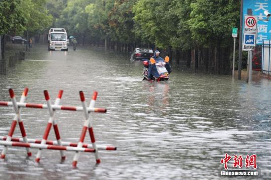 资料图:6月12日,贵阳市民骑电动车在积水路段行驶。记者 贺俊怡 摄 资料图:6月12日,贵阳市民骑电动车在积水路段行驶。记者 贺俊怡 摄