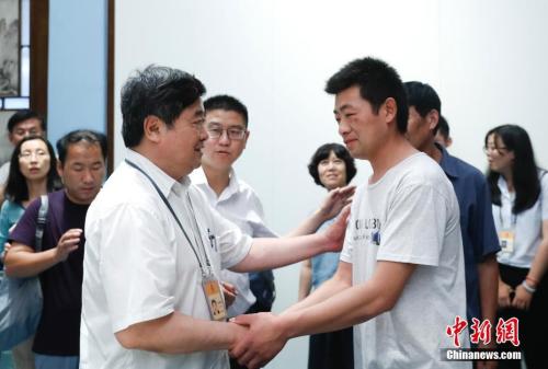 图为故宫博物院院长单霁翔同何刚之子何俊清握手。记者 杜洋 摄 图为故宫博物院院长单霁翔同何刚之子何俊清握手。记者 杜洋 摄