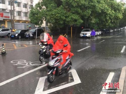 图为北京阜成路,市民雨中骑行。 记者 富宇 摄 图为北京阜成路,市民雨中骑行。 记者 富宇 摄