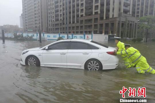 图为:周宇和队员在水中推抛锚的车。 金华公安供图 图为:周宇和队员在水中推抛锚的车。 金华公安供图