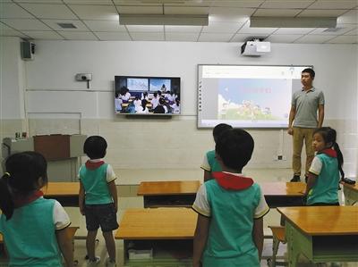 学生们通过远程在线教育系统与海口市滨海第九小学的学生一起上音乐课。 学生们通过远程在线教育系统与海口市滨海第九小学的学生一起上音乐课。