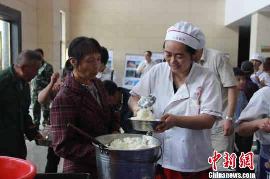 图为爱心企业工作人员为安置点受灾群众盛饭。 图为爱心企业工作人员为安置点受灾群众盛饭。