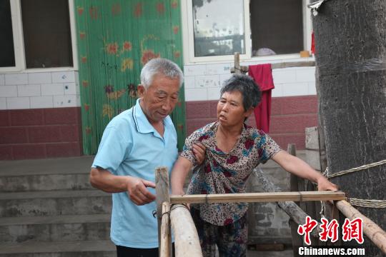 为让妻子慢慢学会走路,李文生每天扶着妻子一遍一遍练习走路。 李院红 摄 为让妻子慢慢学会走路,李文生每天扶着妻子一遍一遍练习走路。 李院红 摄