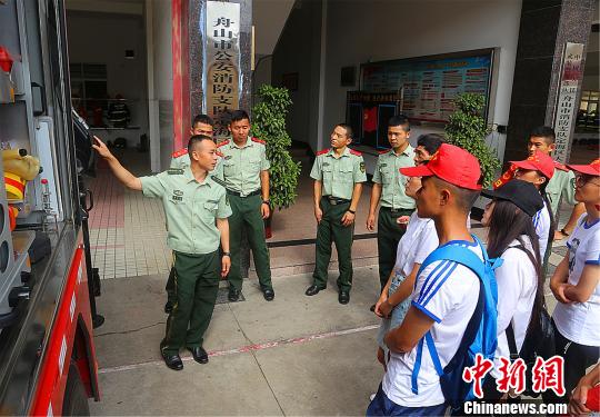 图为：消防官兵给剪纸实践团的学生们介绍消防器材。　史冬伟 摄