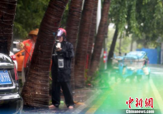 7月16日,一位正在清扫街道残枝落叶的三亚环卫工人在风雨中用餐。 尹海明 摄 7月16日,一位正在清扫街道残枝落叶的三亚环卫工人在风雨中用餐。 尹海明 摄